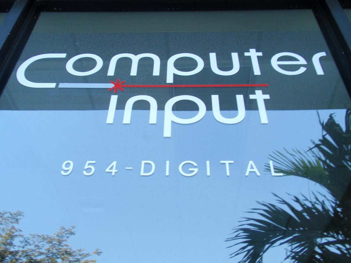 The Computer Input sign on the office window, with palms reflected in the glass