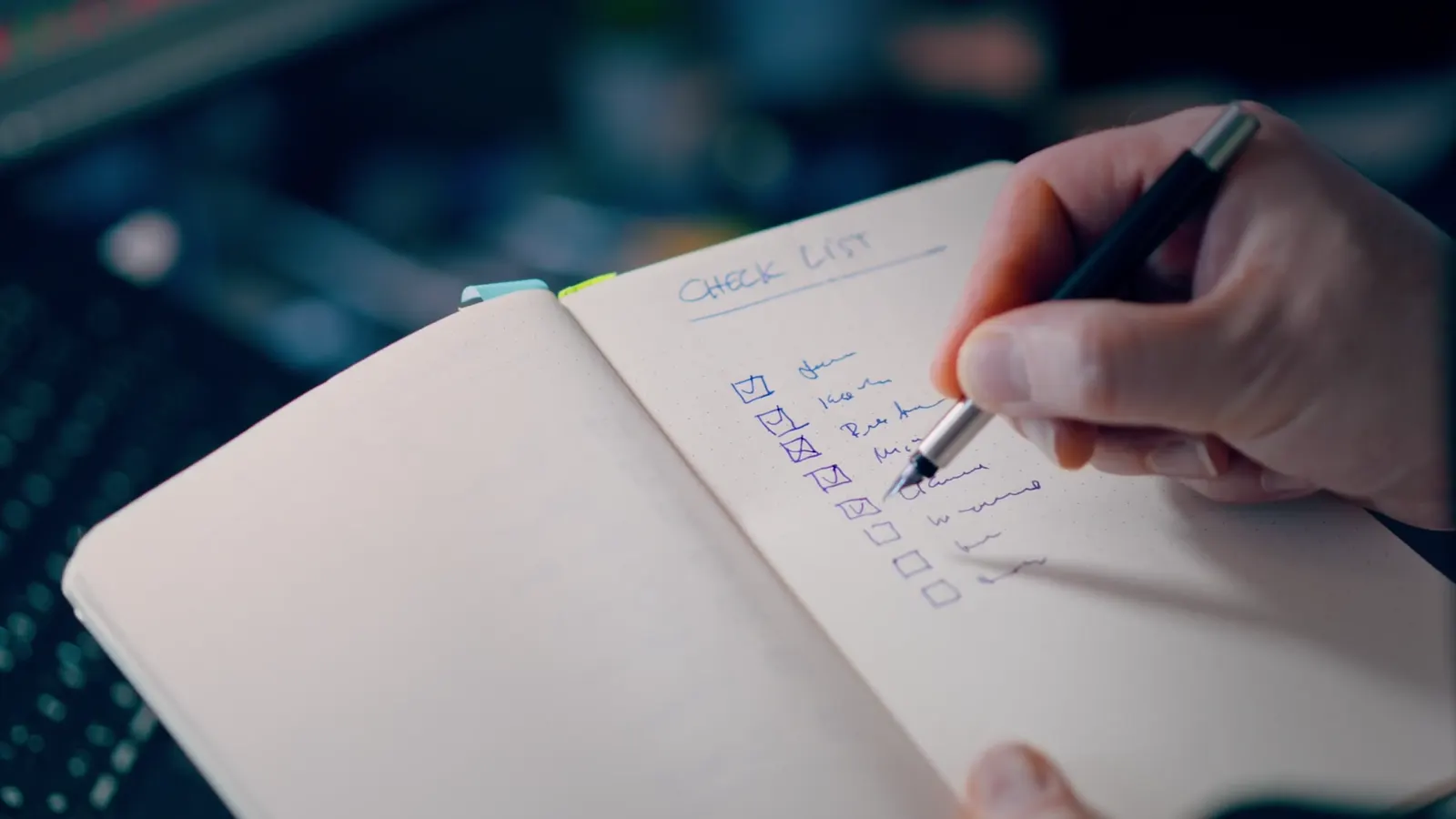 A hand ticking off a checklist in a notebook